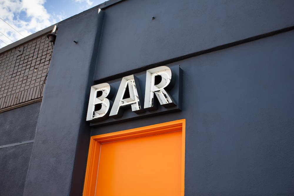 Front of a black building location with a sign saying "Bar"